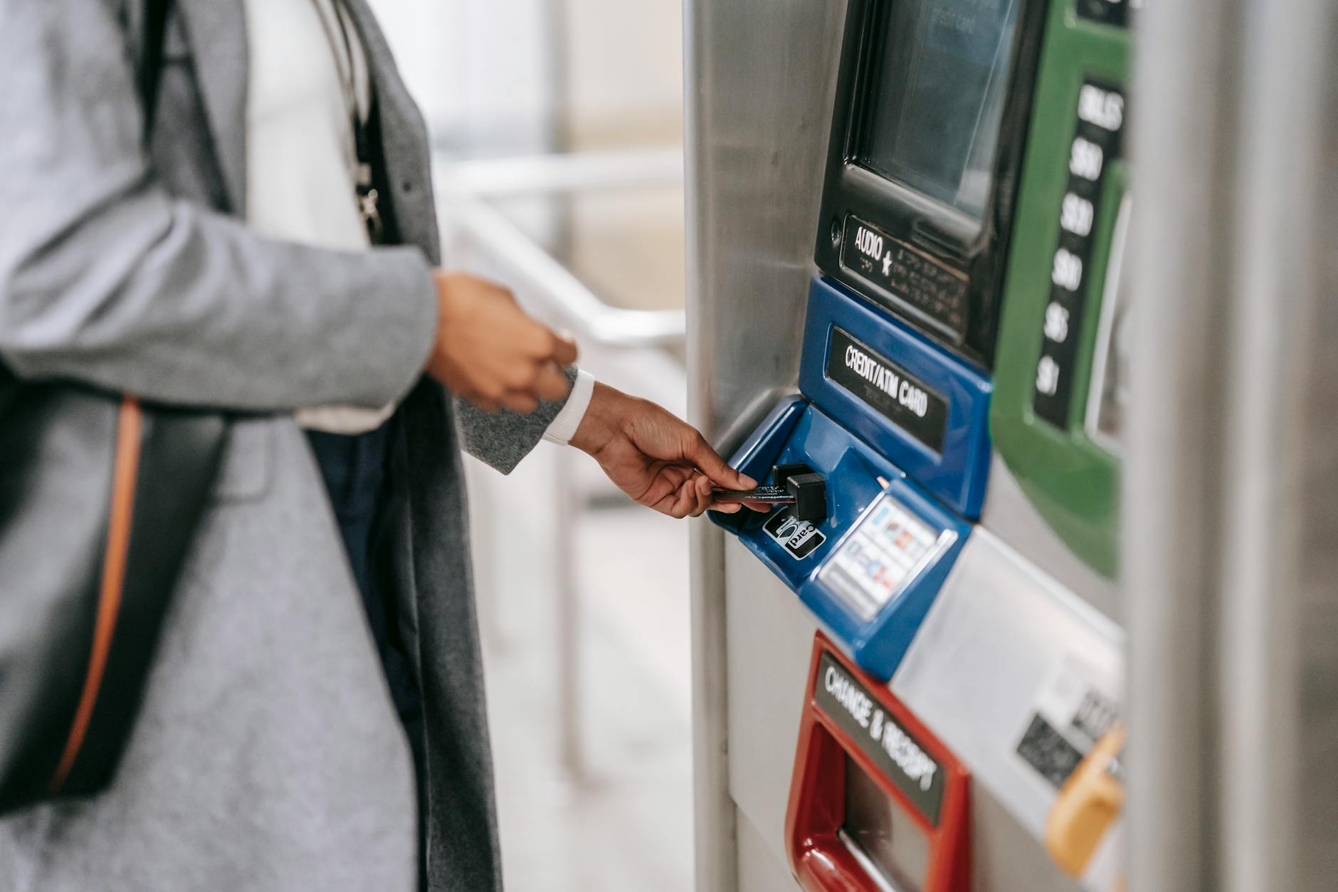 Kobieta kupuje bilet w automacie biletowym za pomocą karty płatniczej