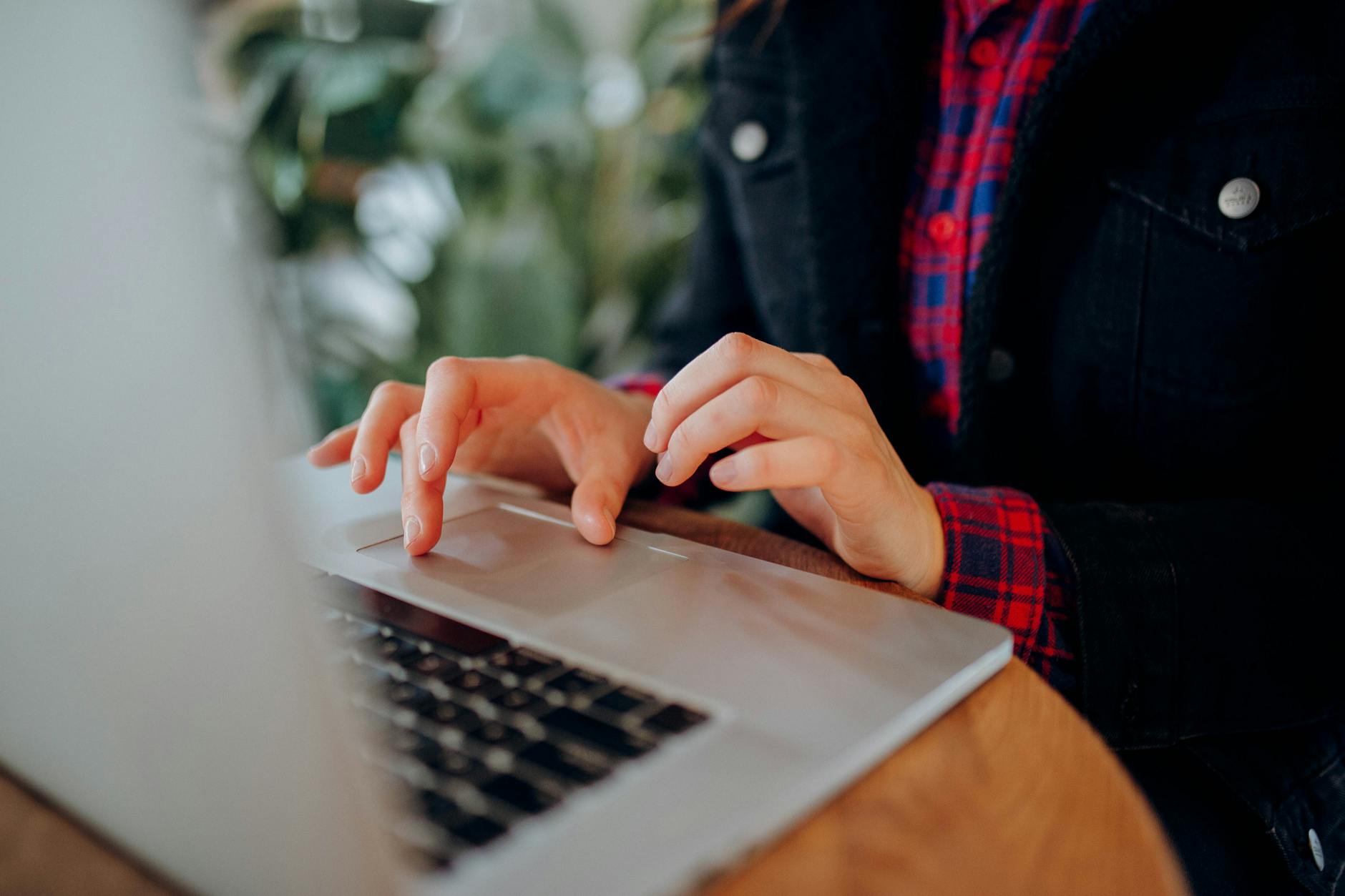 Osoba w koszuli w kratę pisząca na laptopie z Windows 11