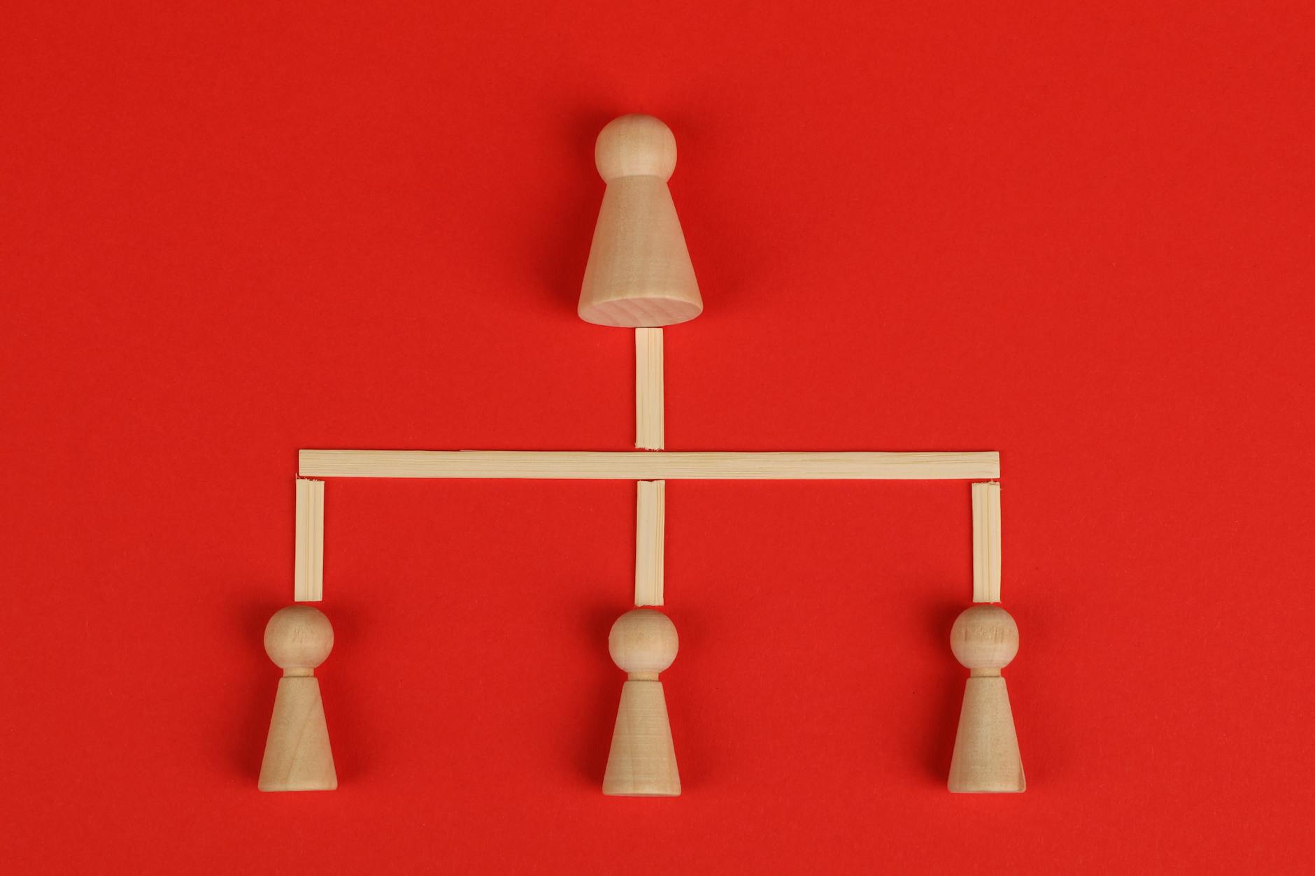 Drewniane klocki tworzące hierarchiczną strukturę na czerwonym tle