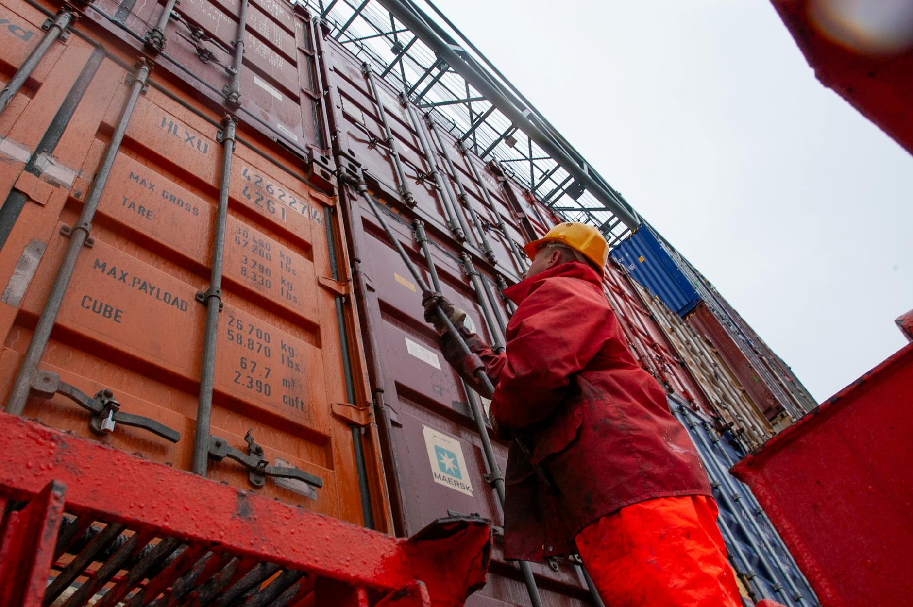Pracownik portowy zabezpiecza kontenery cargo w deszczu