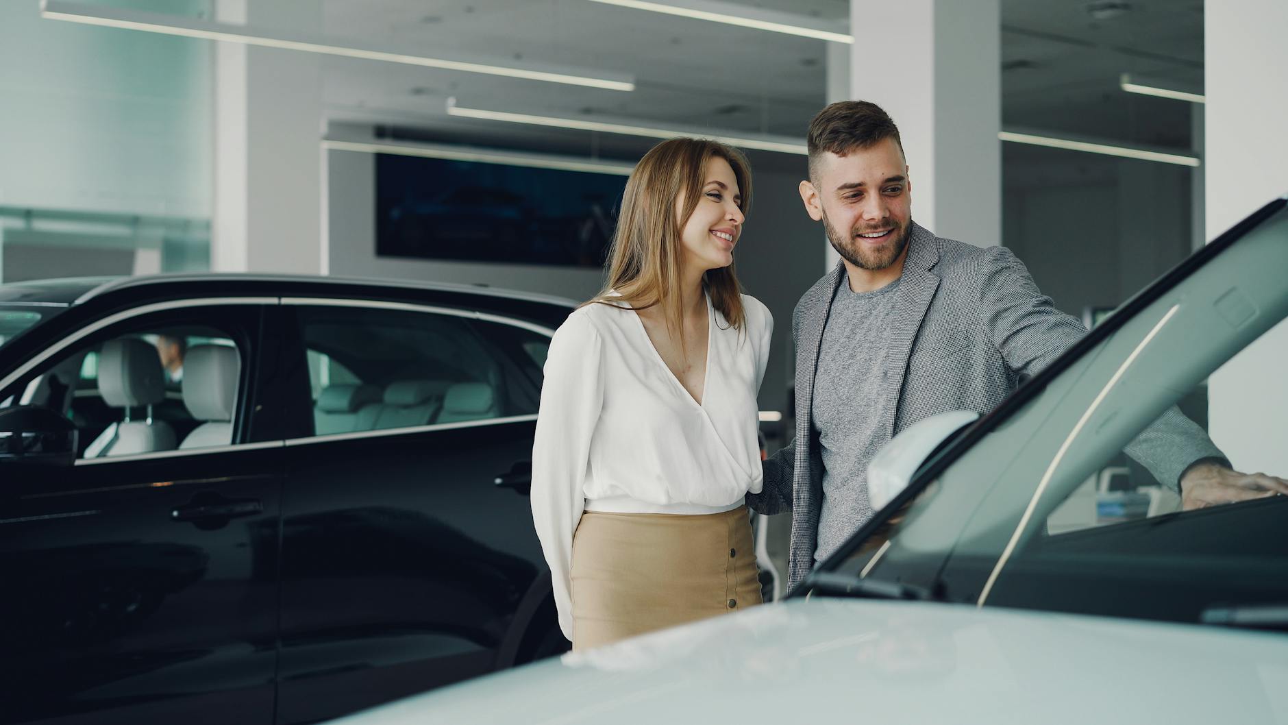 Jak wybrać pierwszy samochód premium: praktyczny przewodnik dla początkujących miłośników luksusowej motoryzacji Uśmiechnięta para ogląda samochód premium w salonie samochodowym