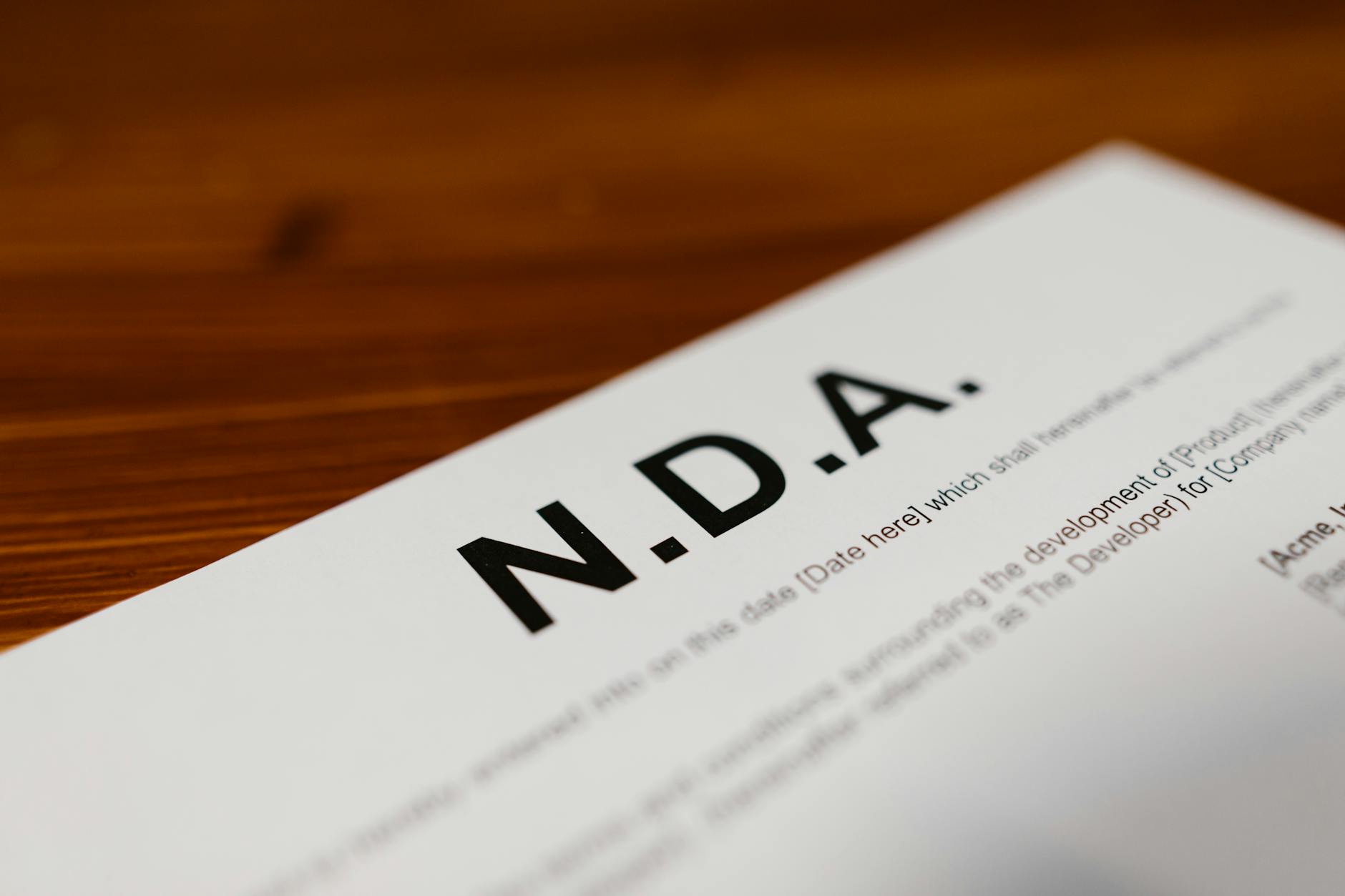 Zbliżenie na dokument NDA z klauzulami licencyjnymi na drewnianym biurku