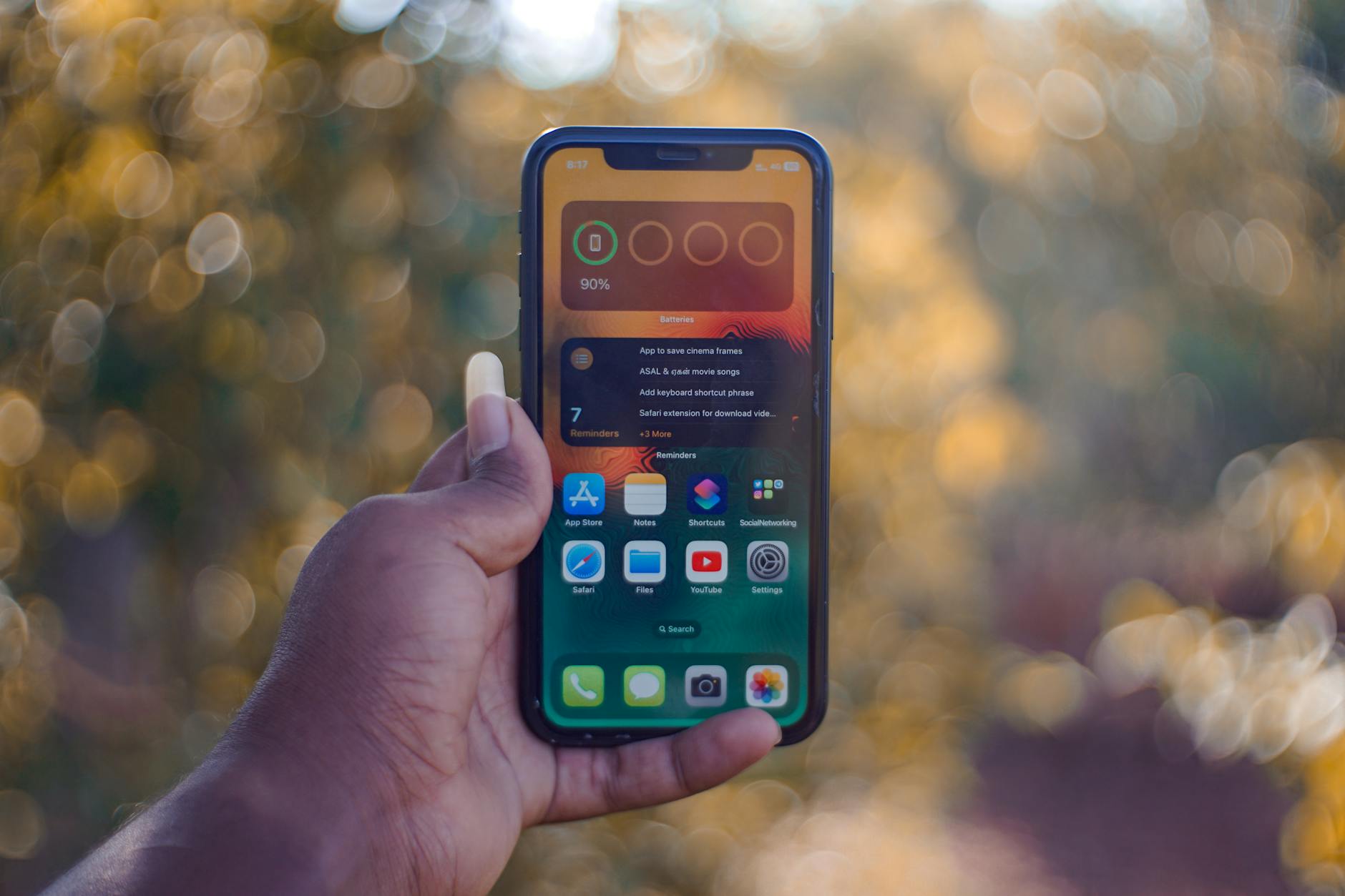 Dłoń trzymająca smartfon na tle rozmytego, jasnego pleneru