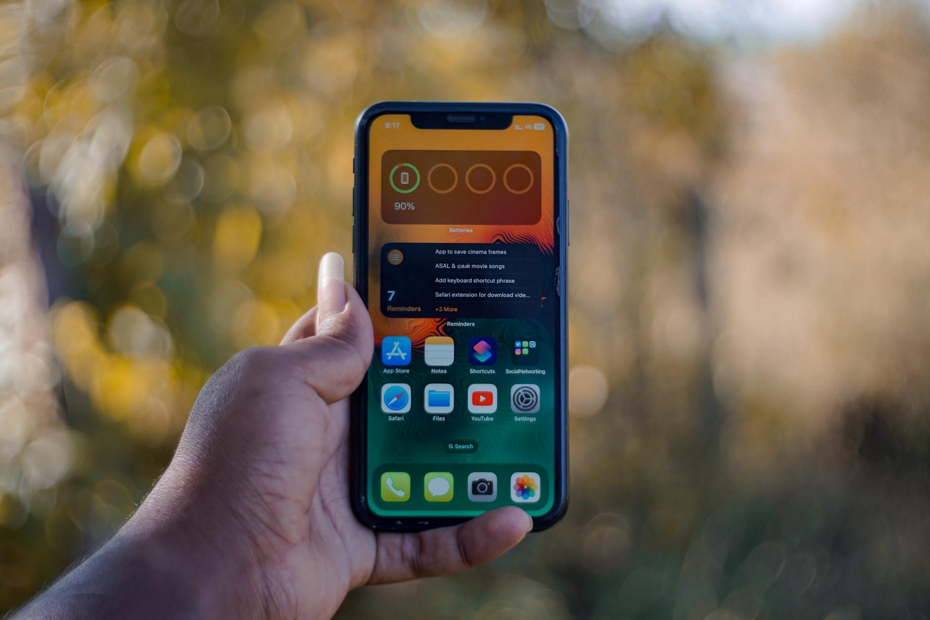 Dłoń trzymająca smartfon z aplikacjami na ekranie na zewnątrz