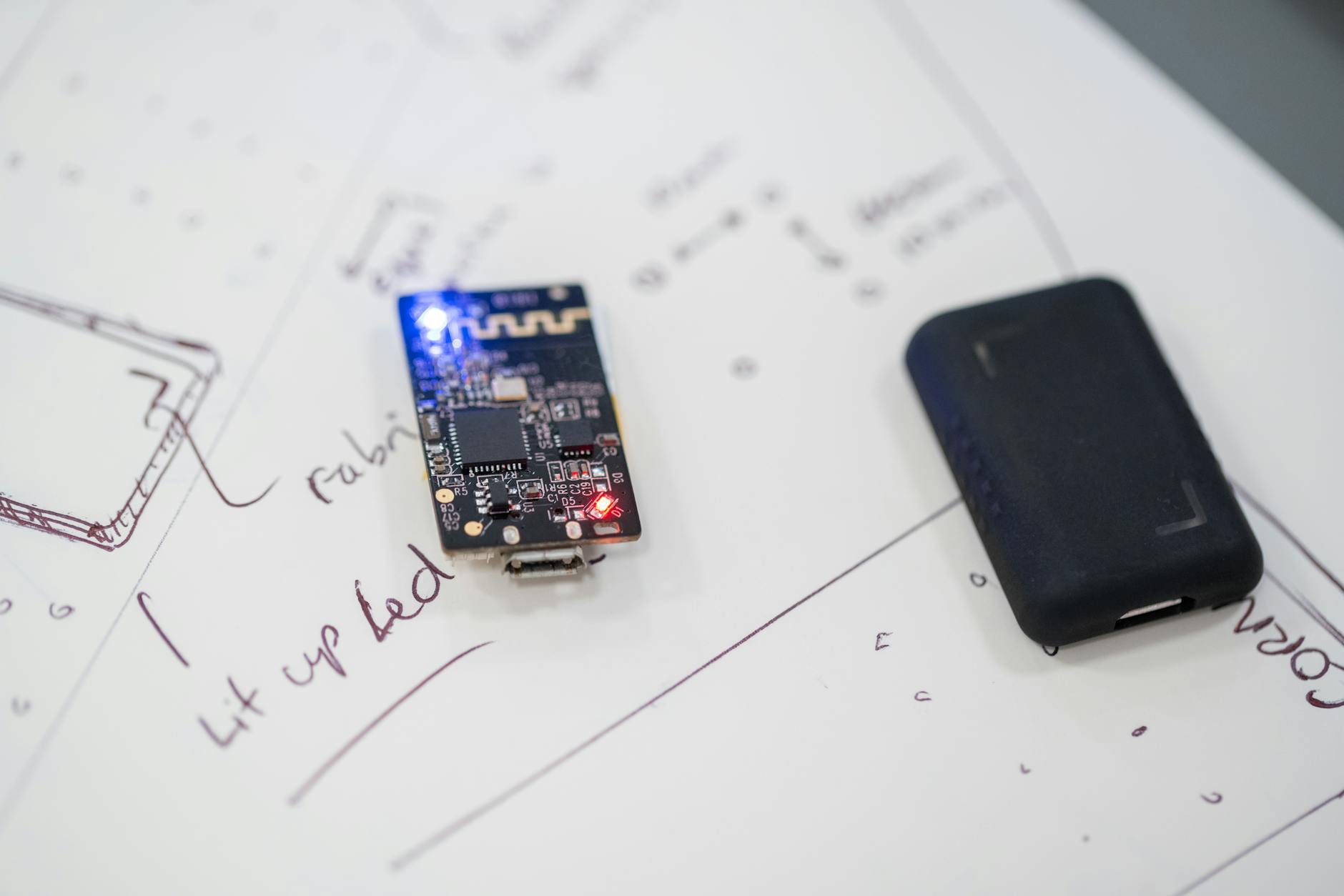 Mikroprocesor IoT na płytce PCB leżącej na technicznych szkicach