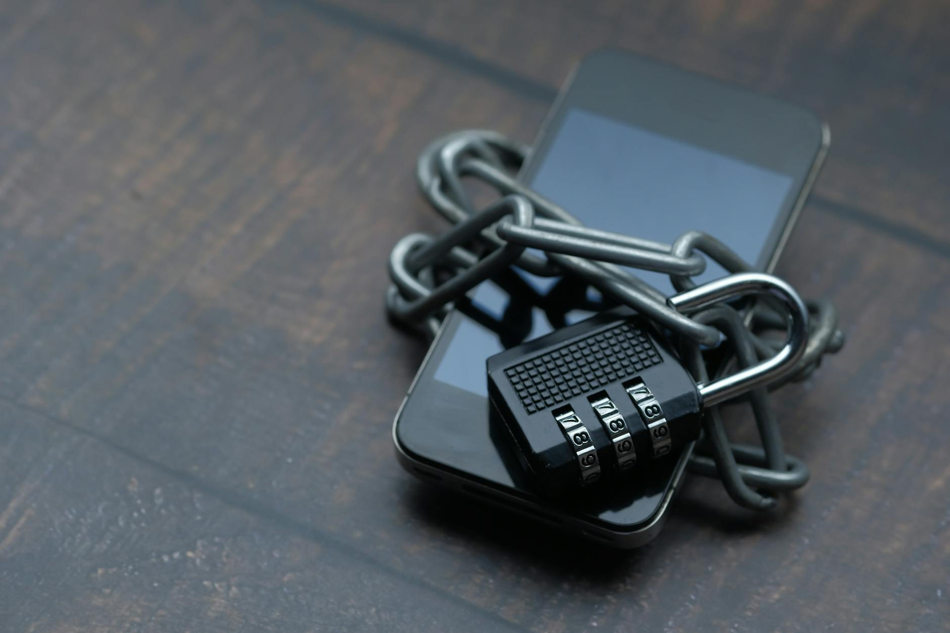 Smartfon owinięty łańcuchem z kłódką symbolizujący silne szyfrowanie