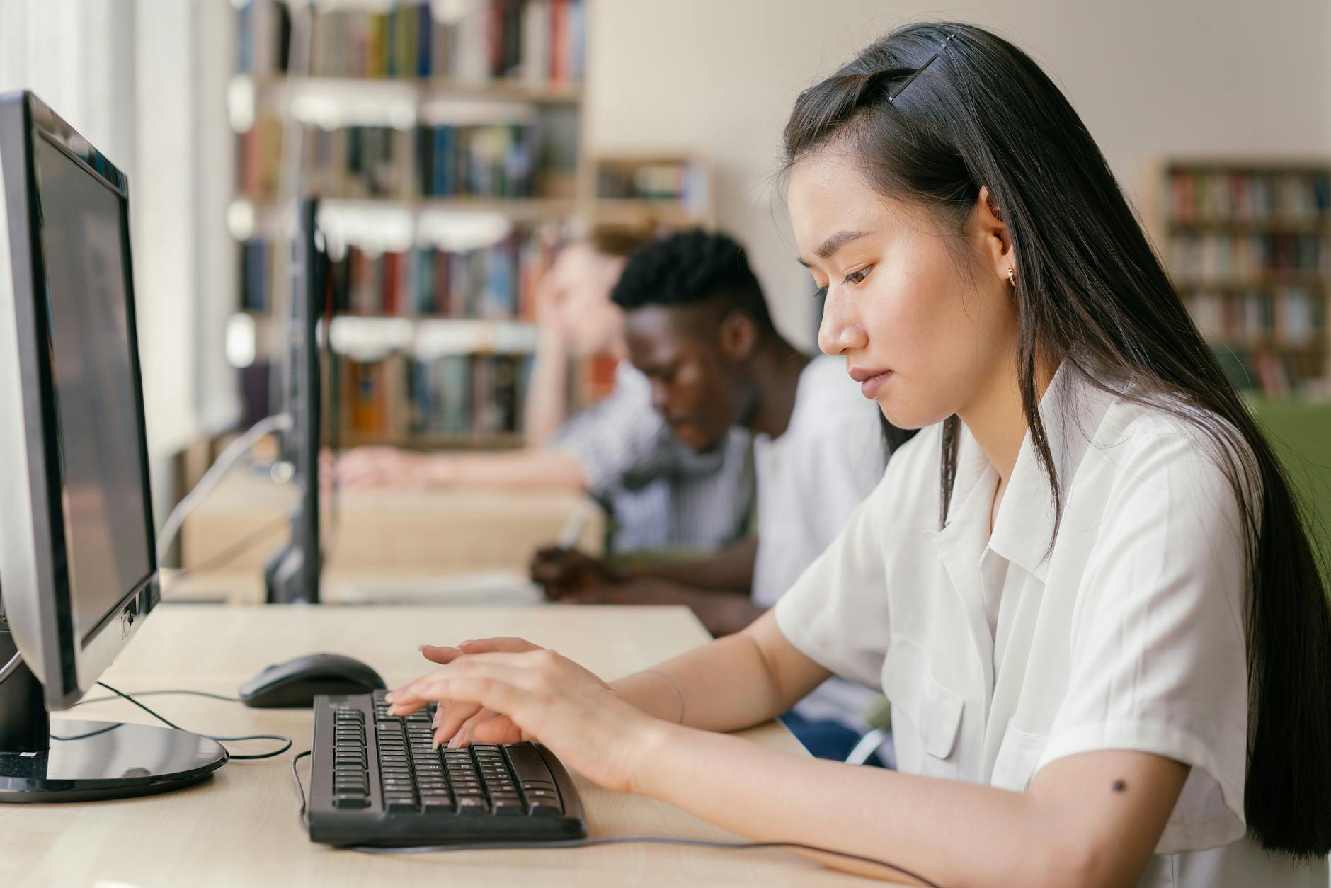Studenci programujący na laptopach w bibliotece podczas nauki NLP