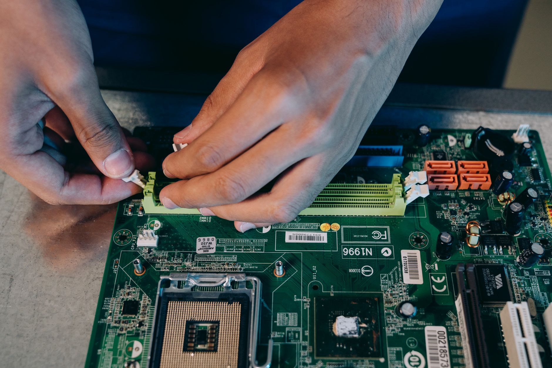 Dłonie montujące płytę główną podczas składania komputera PC