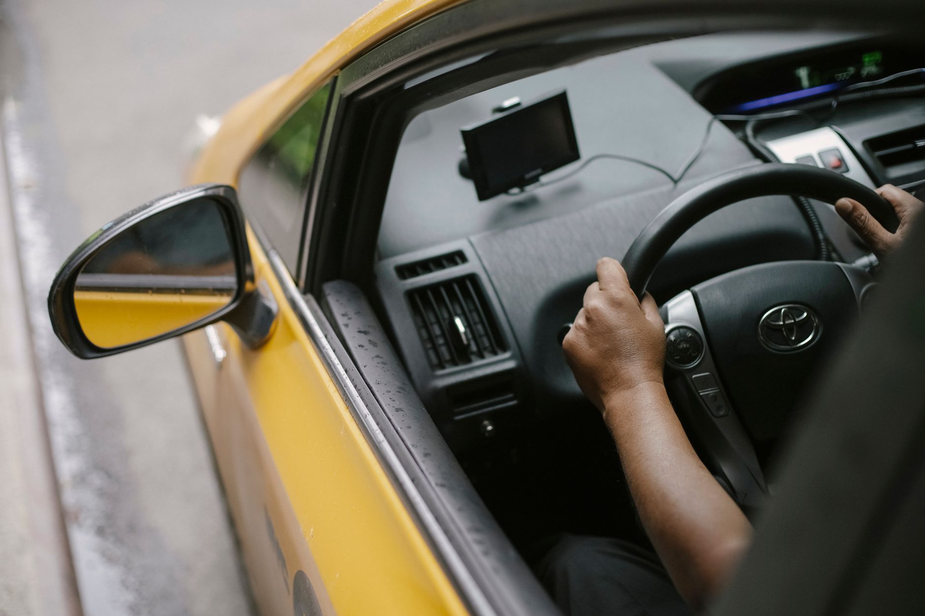 Kierowca prowadzi żółtą taksówkę z nawigacją GPS w ruchu miejskim