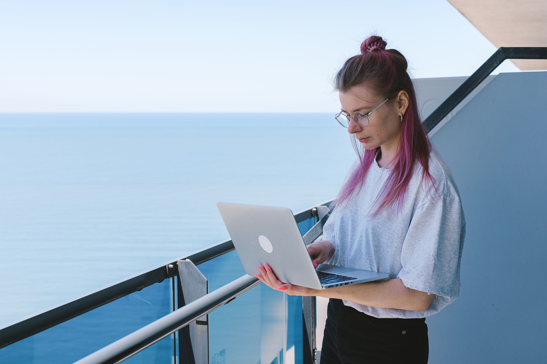 Młoda freelancerka IT pracuje z laptopem nad morzem w słoneczny dzień