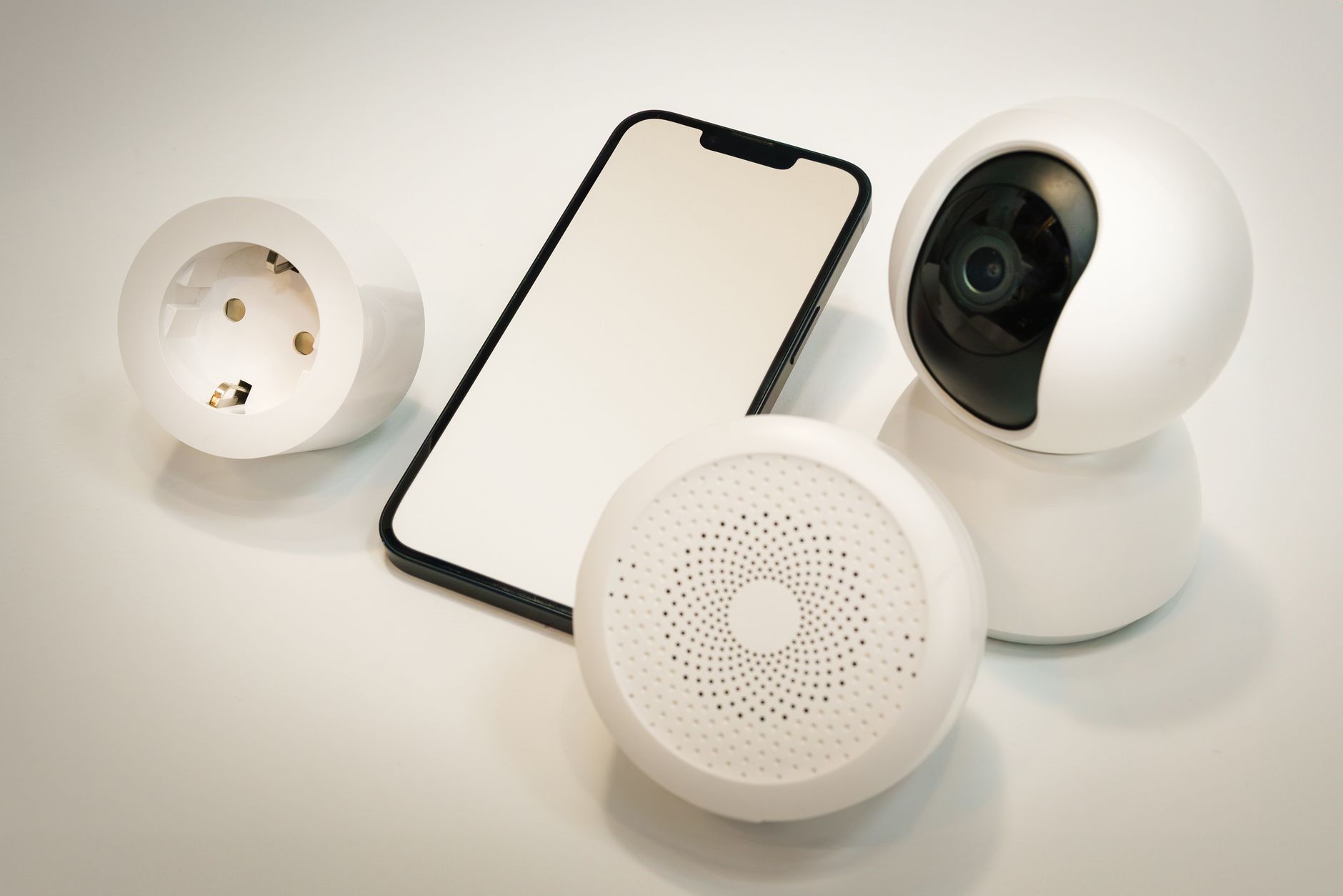 Urządzenia smart home: kamera, głośnik i smartfon na białym tle