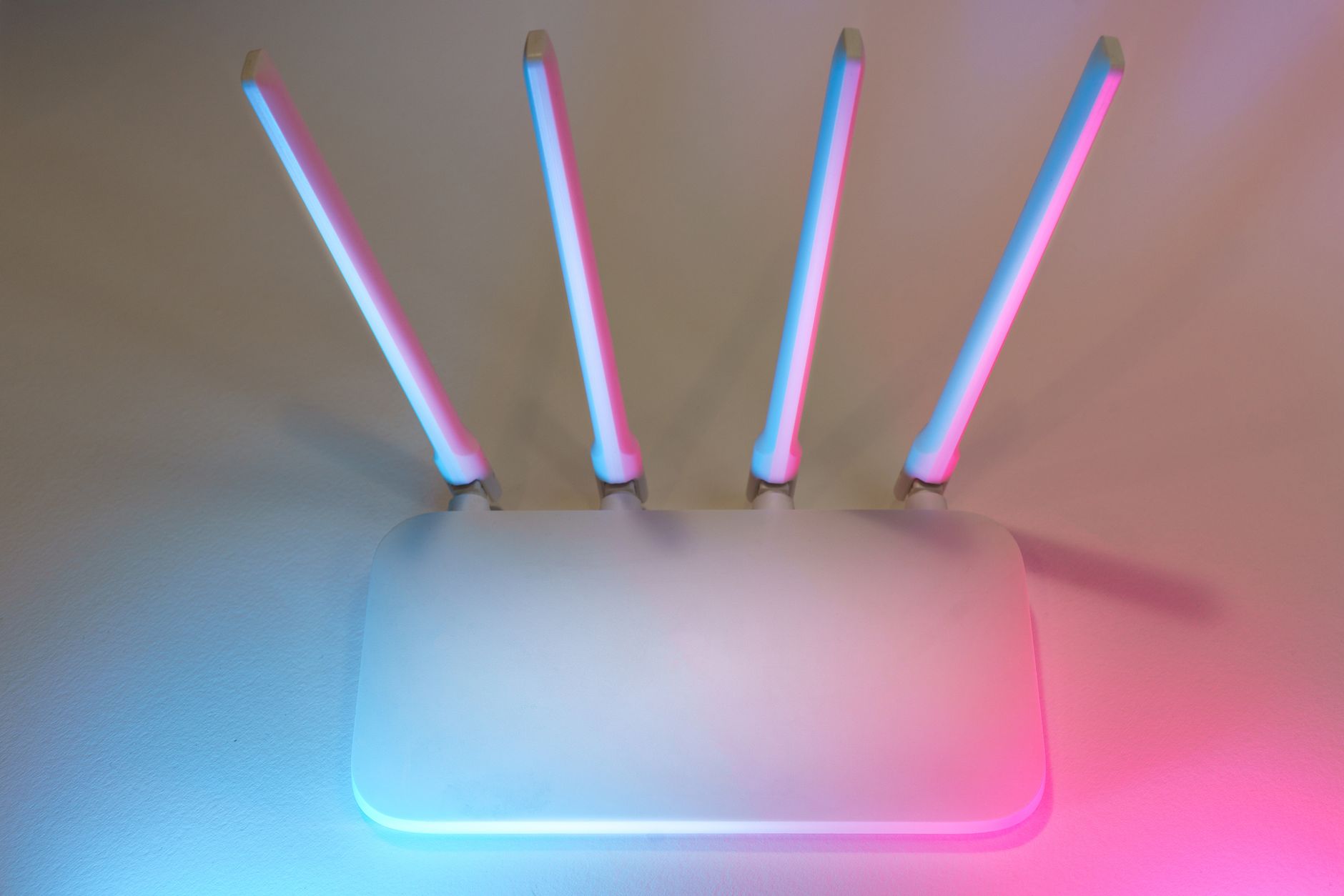 Nowoczesny biały router WiFi z czterema antenami w niebiesko-różowym świetle Nowoczesny biały router WiFi z czterema antenami w niebiesko-różowym świetle
