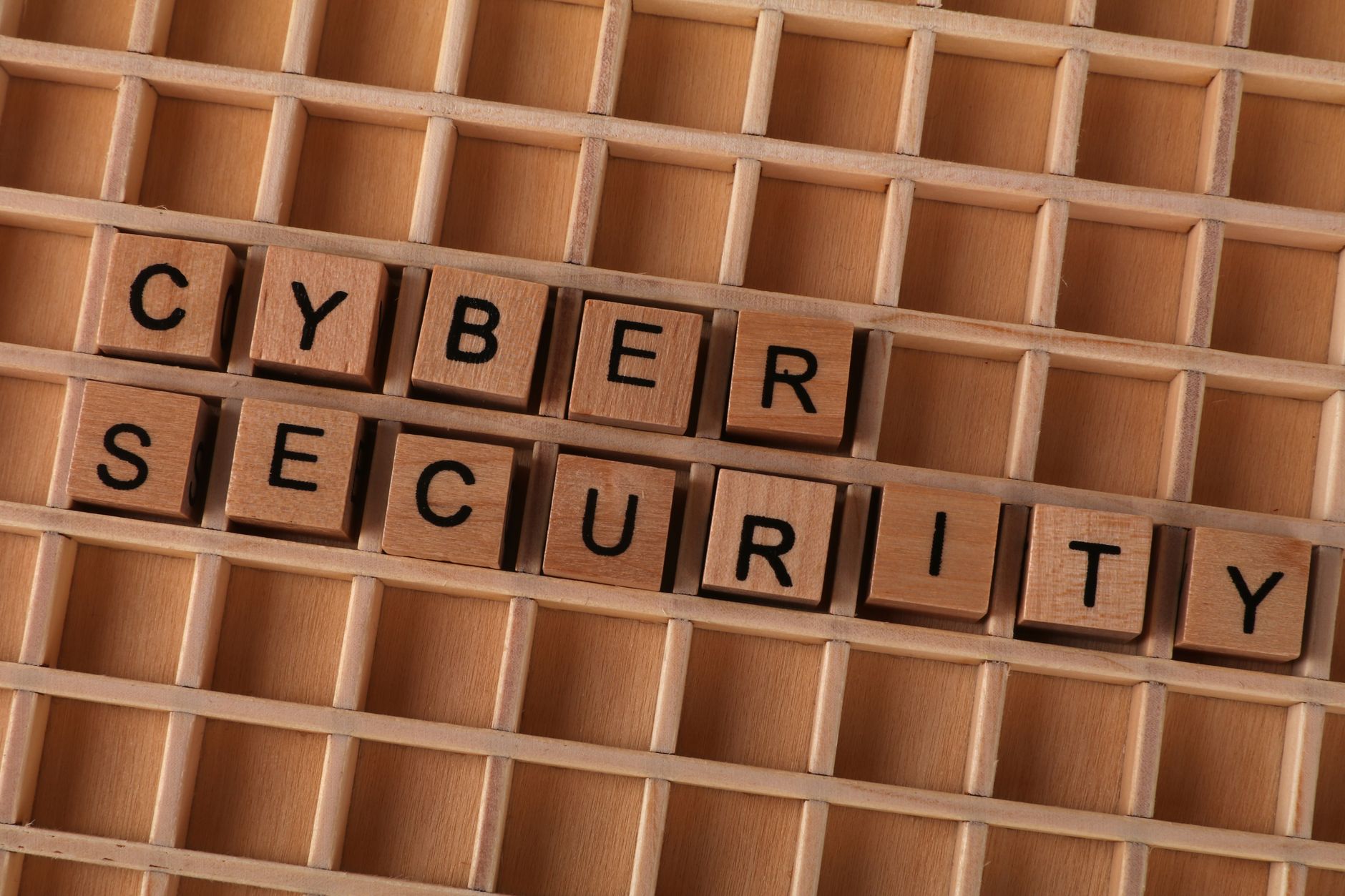 Drewniane klocki z napisem cyber security na tle drewnianej kratki