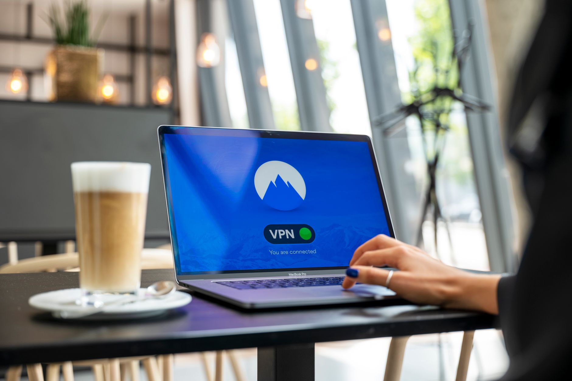 Czy publiczne Wi Fi jest bezpieczne? Zasady, które ratują dane Osoba korzystająca z laptopa z włączonym VPN w kawiarni