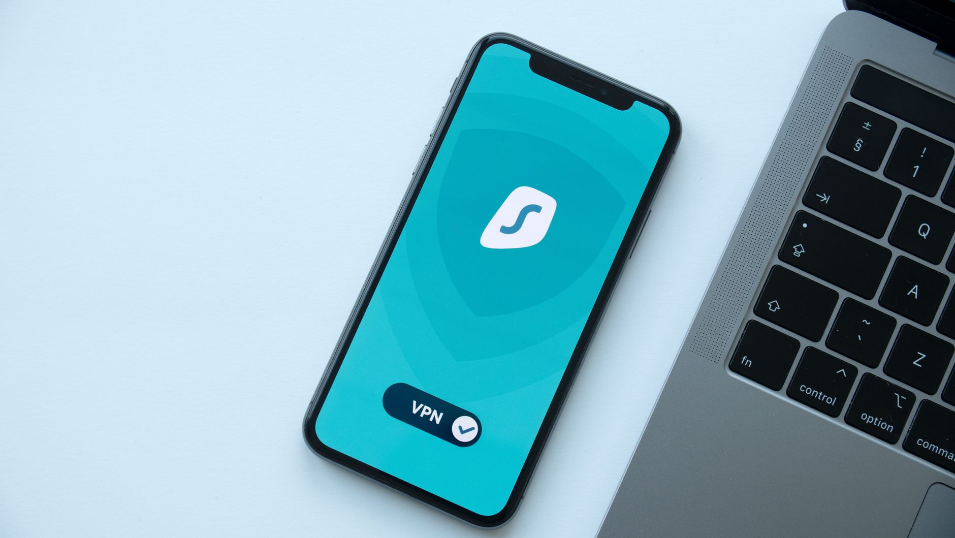 Smartfon z aplikacją VPN obok laptopa na biurku